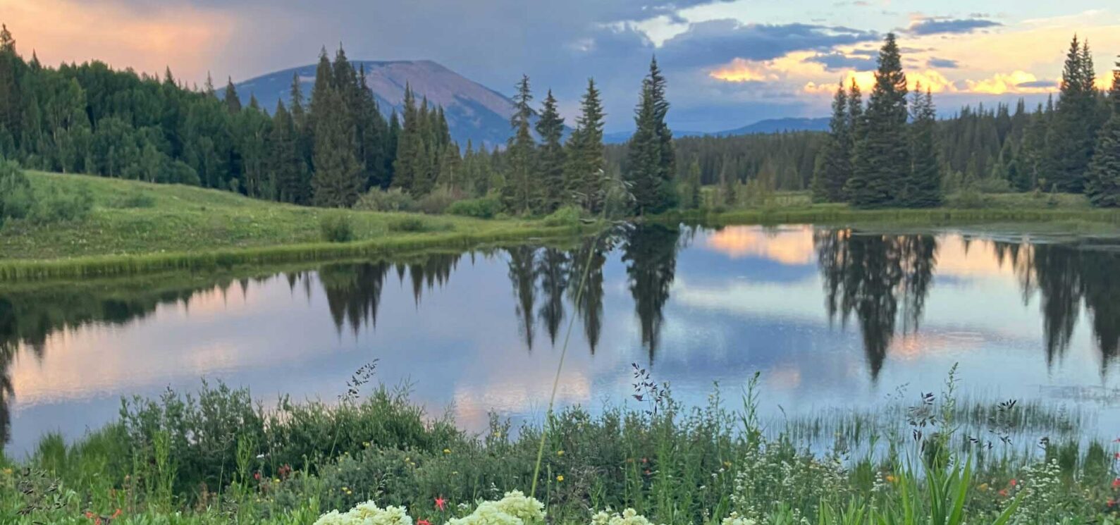 glassy pond below mountains at sunset