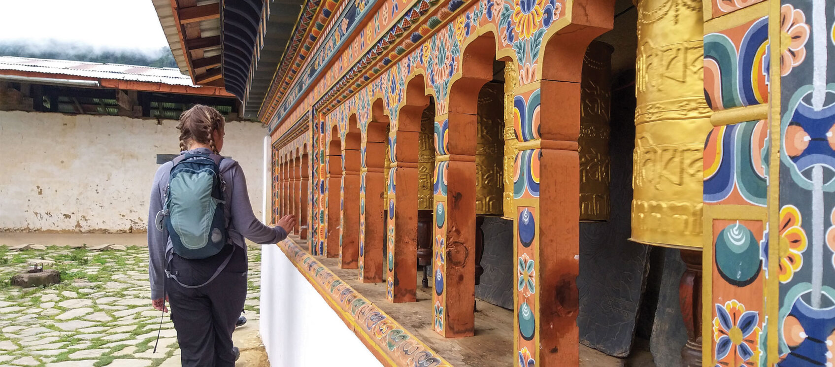 girl walking past prayer wheels